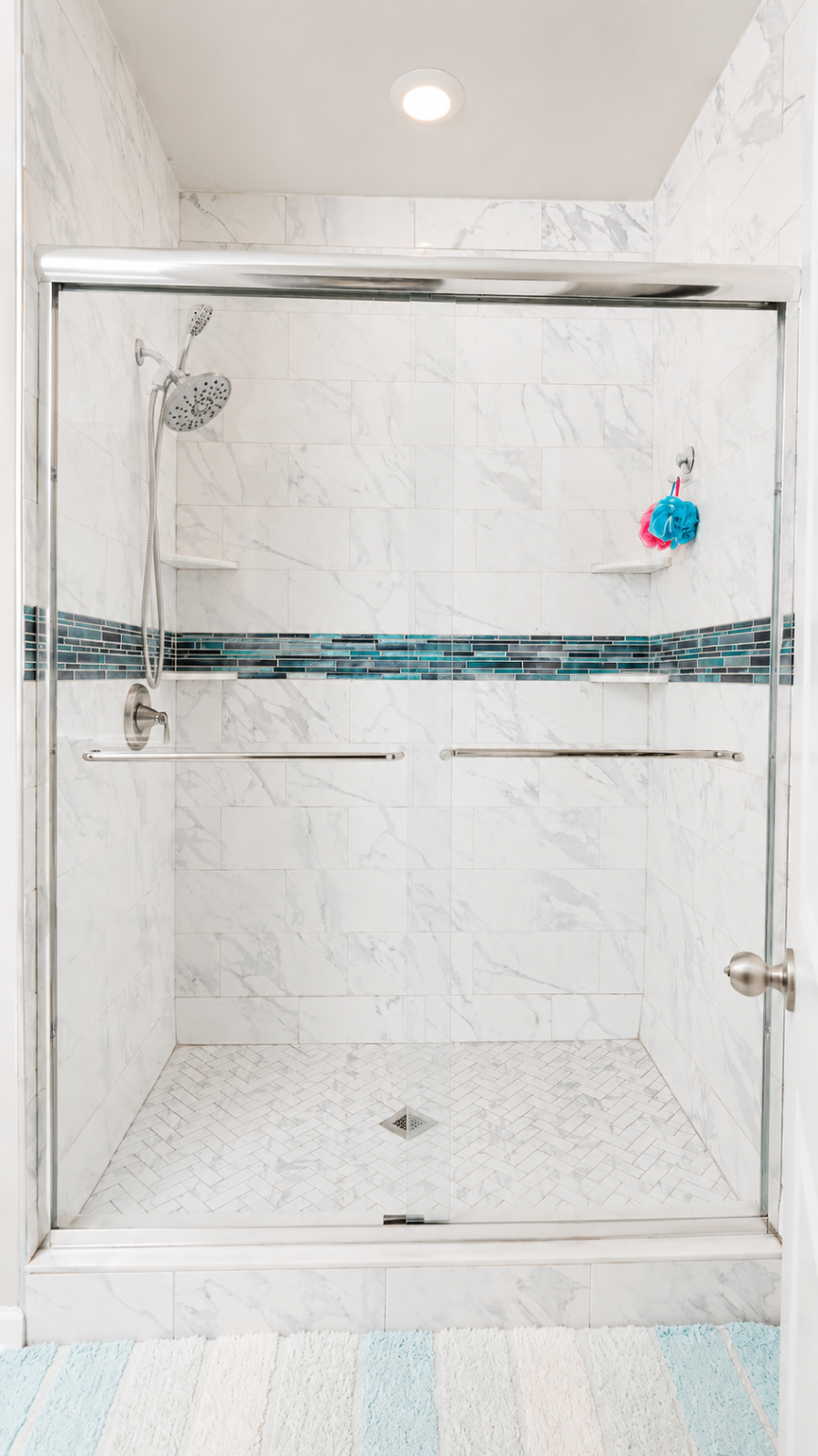 Close view of the updated primary shower with herringbone floor and blue accent tile