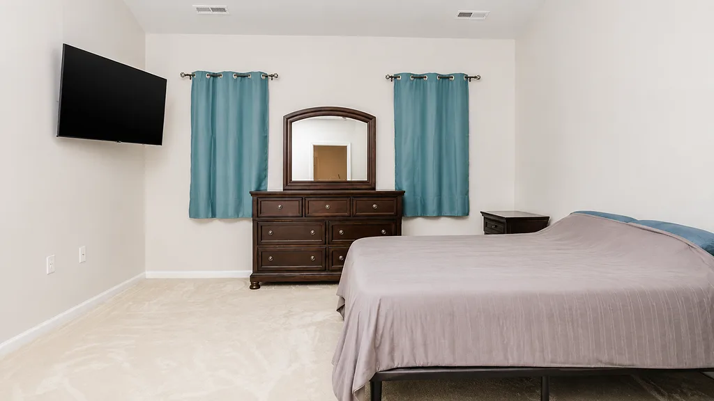 Spacious secondary bedroom at 222 Lothian with dresser and blue curtains