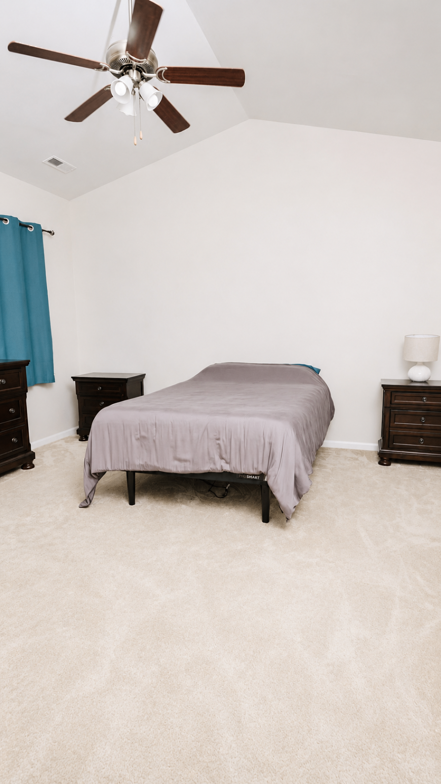 Bedroom with vaulted ceiling and warm wood nightstands